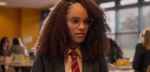 Yasmin Finney plays young teen Elle in Heartstopper. In this picture, the character is wearing a British school uniform with a dark jacket, white shirt and red striped tie