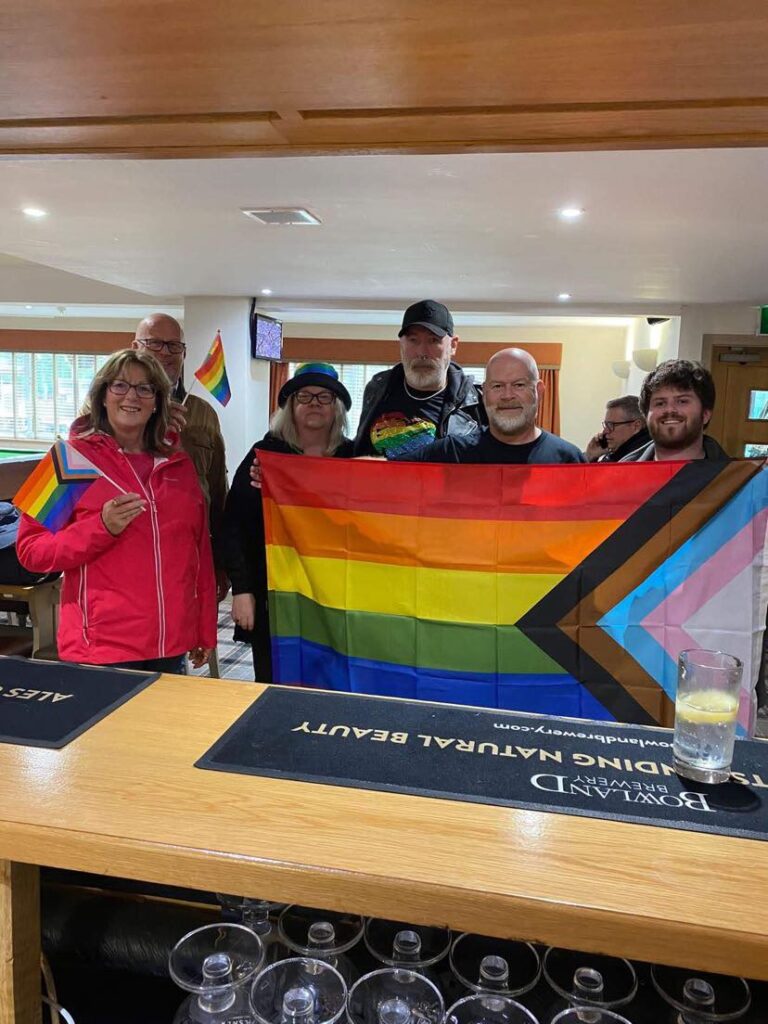 New Longton residents waving LGBTQ+ flags in the local pub