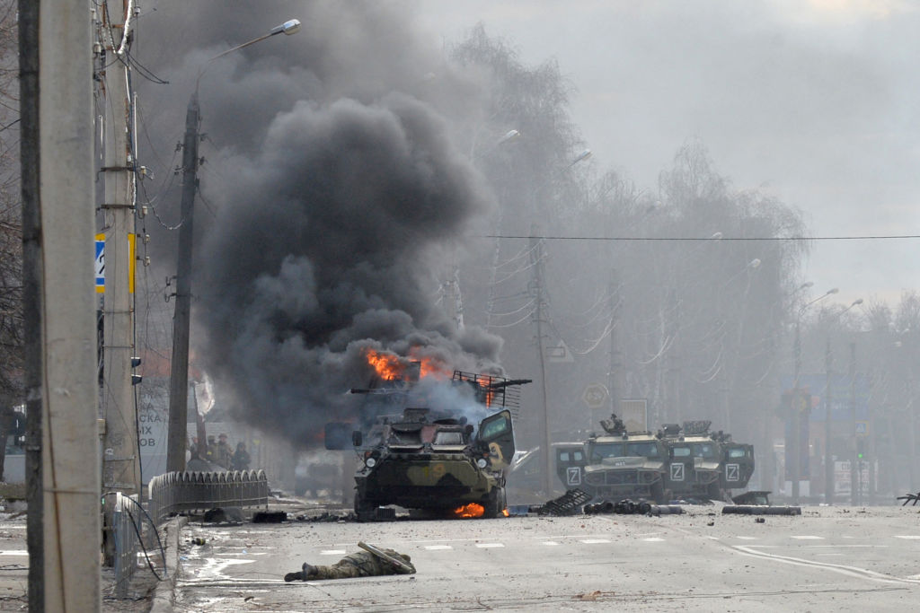 An unidentified soldier's body lies near a burning Russian Armoured personnel carrier (APC) during fighting with the Ukrainian armed forces in Kharkiv, on February 27, 2022.