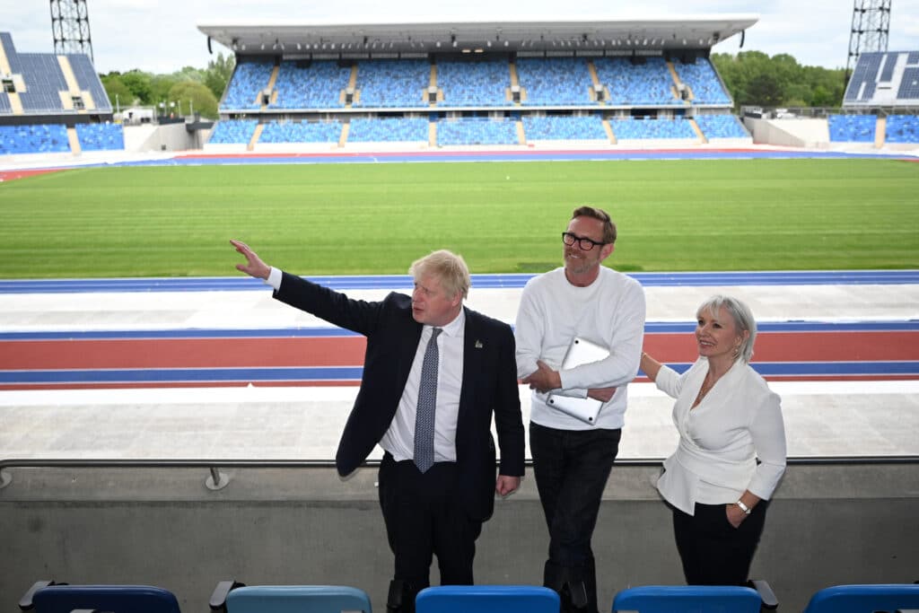 Prime minister Boris Johnson (L) and culture secretary Nadine Dorries (R) stand in a football stadium