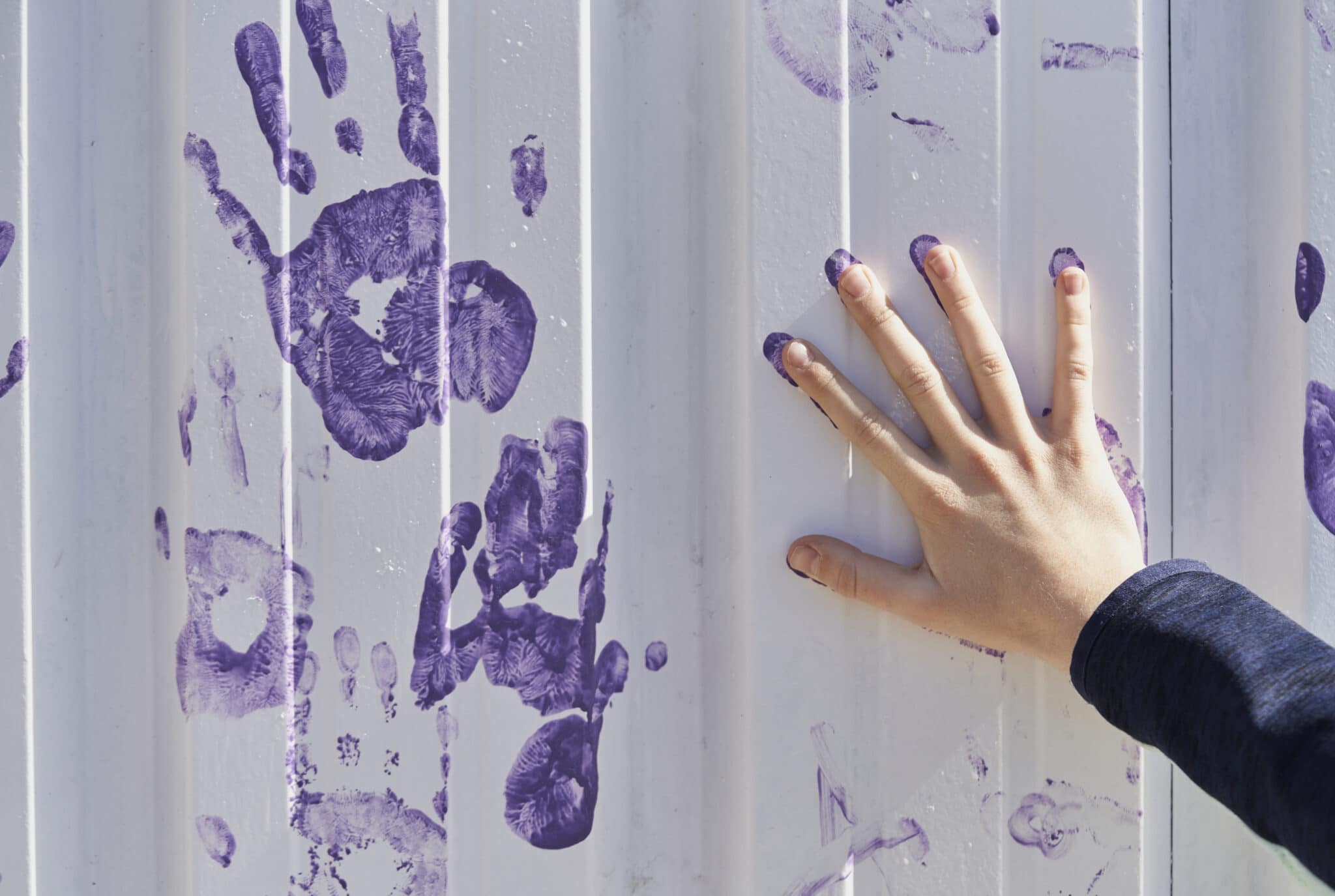 Close-up of a person marking handprints on the white wall.