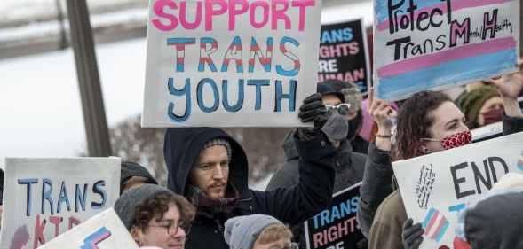 Families hold placards at a rally against increasing legislative attacks on trans kids across the US