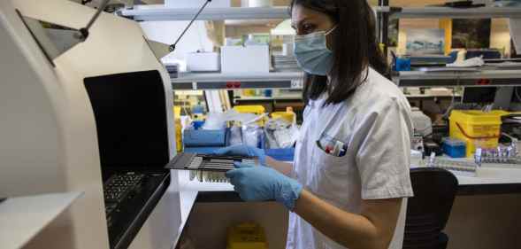 A medical laboratory technician places closes an automated nucleic acid extractor with suspected monkeypox samples inside