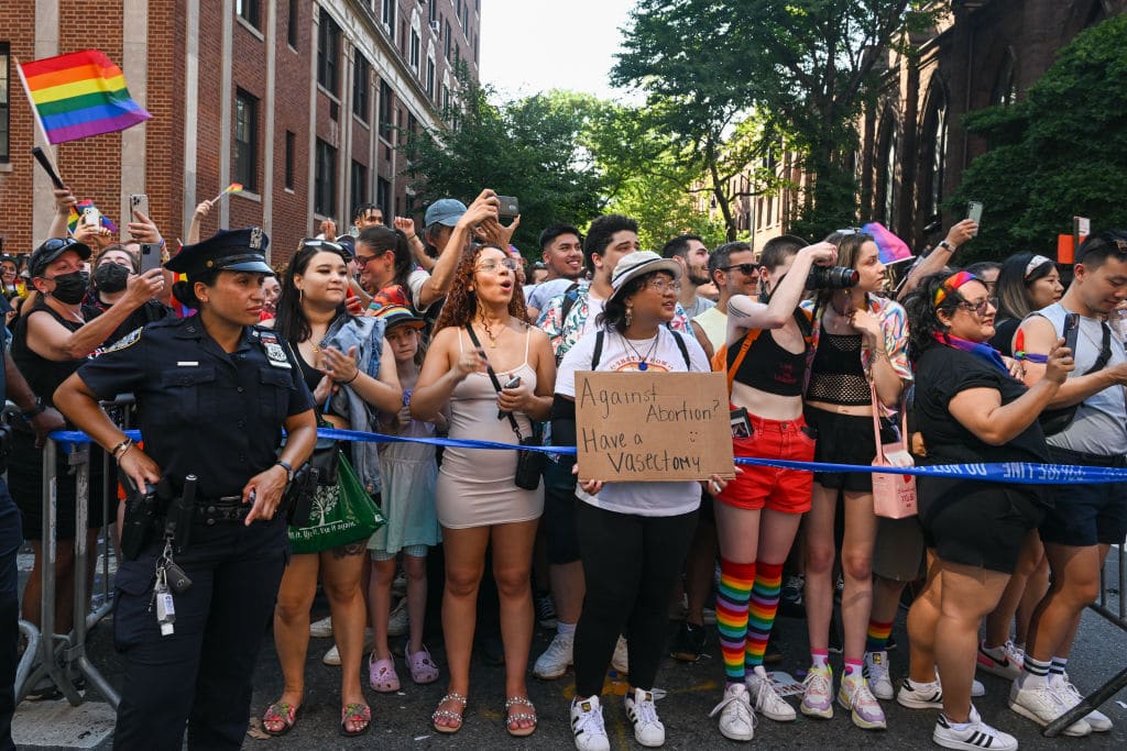 A person holds a "against abortion, have a vasectomy" sign in the New York City Pride Parade.