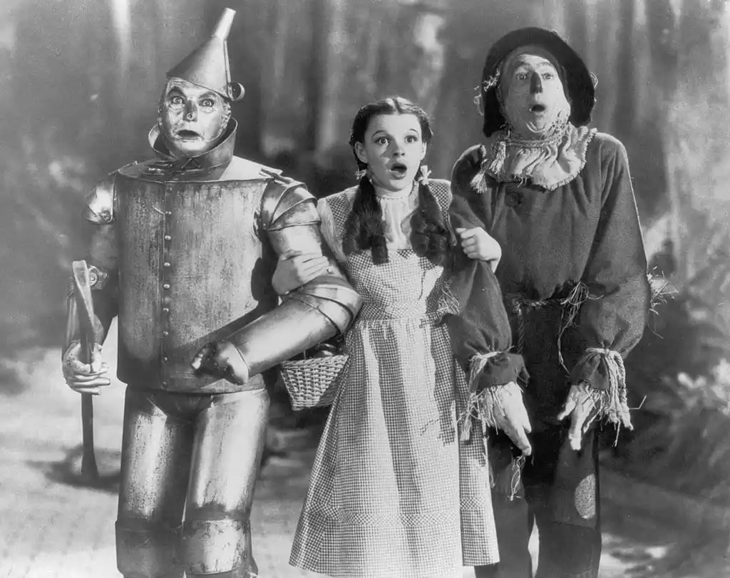 The Tin Man (Jack Haley), Dorothy (Judy Garland) and the Scarecrow (Ray Bolger) set off on their quest for fulfillment in The Wizard of Oz. 