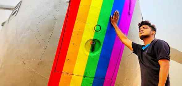 Trans pilot Adam Harry rests his hand on a rainbow painted aeroplane