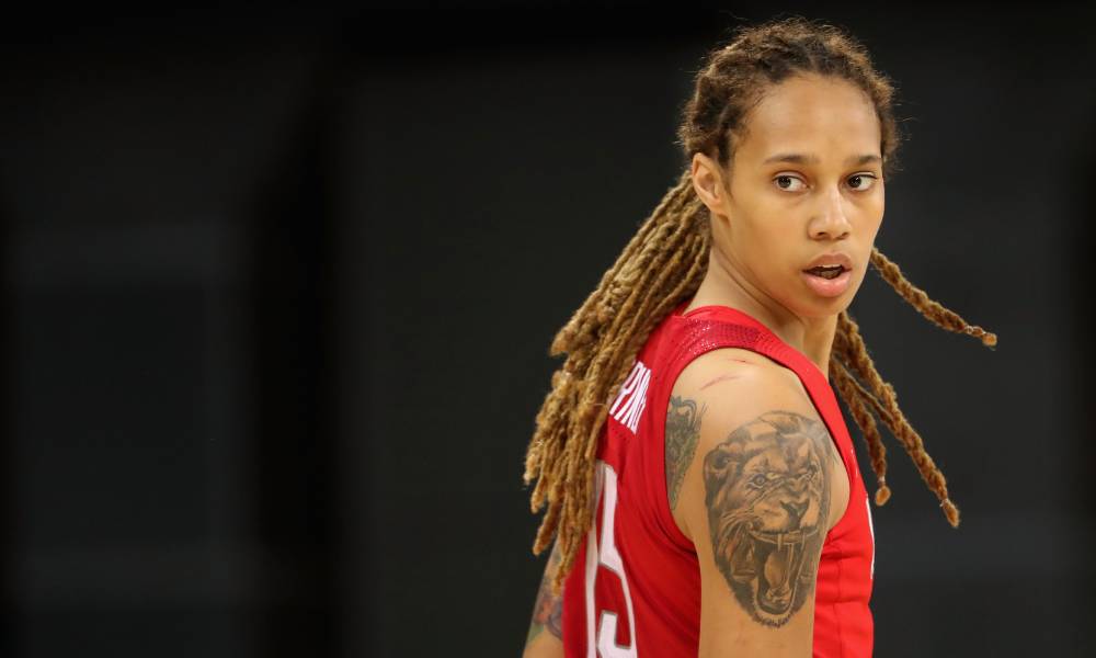 Brittney Griner looks over her shoulder as she wears a red basketball jersey with her hair styled in locks