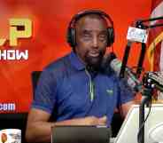 esse Lee Peterson wears a blue short-sleeved shirt as he speaks into a microphone and wears black headphones with two tablets placed in front of him