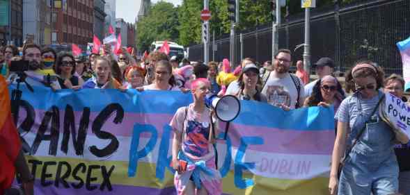 Trans and Intersex Pride co-founder Ollie Bell holds a megaphone in front of a banner during a Dublin Pride event