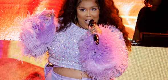 Lizzo in a purple two piece with furry sleeves, singing