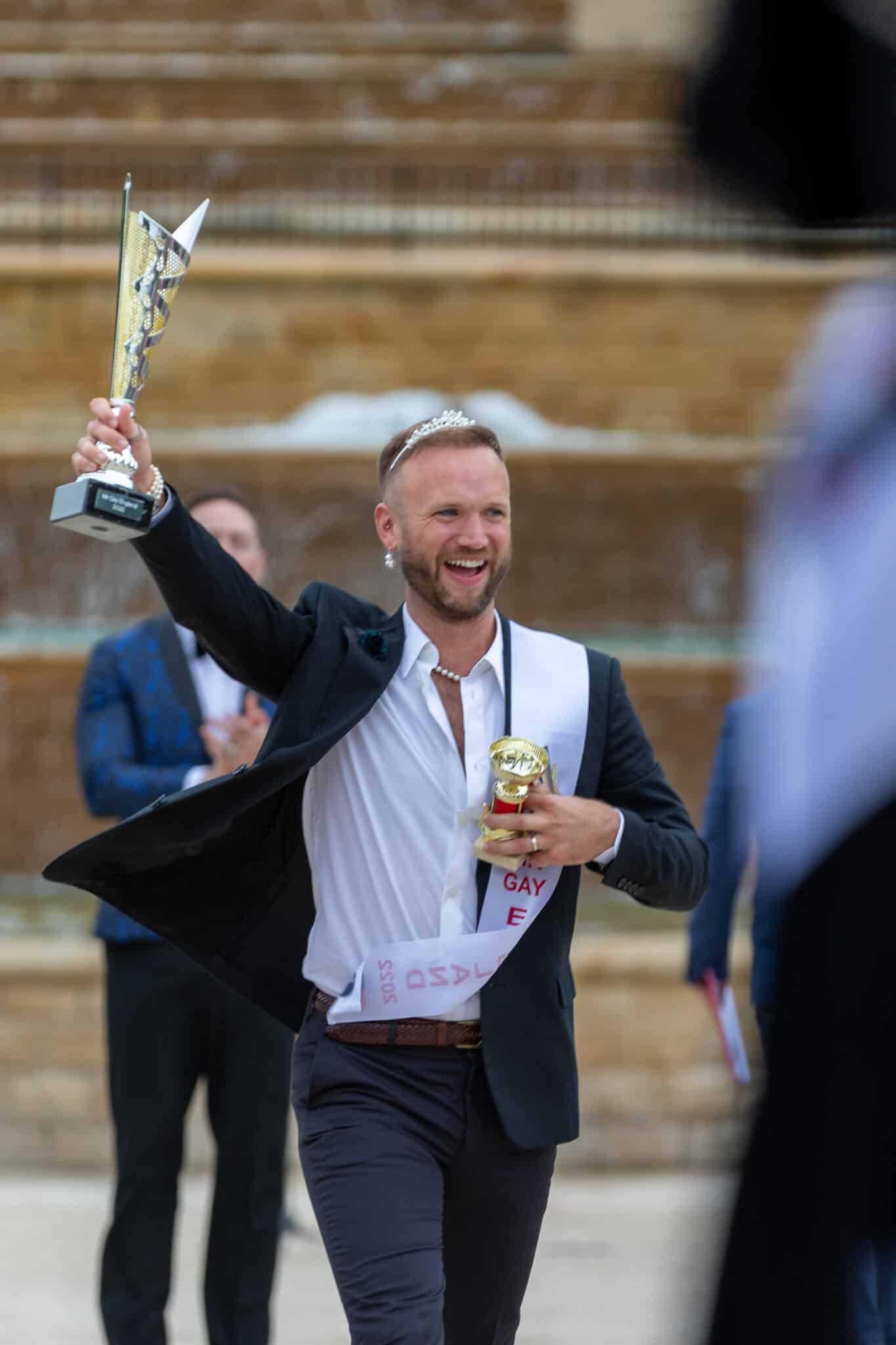 Man in suit holding trophy in the air 