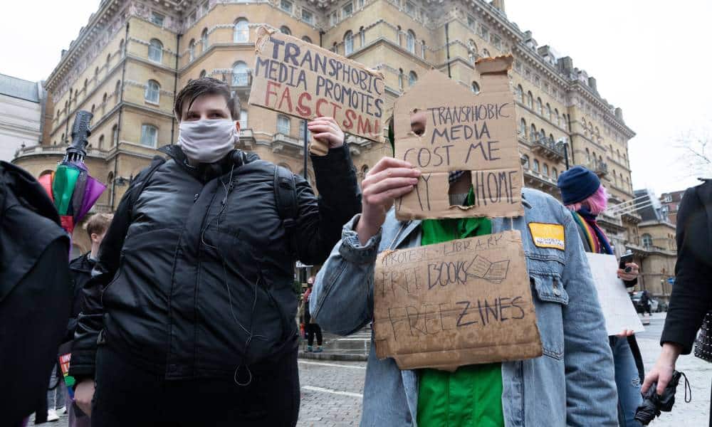 Two people are pictured in a protest outside the BBC in which people denounced anti-treans reporting by the media organisation.