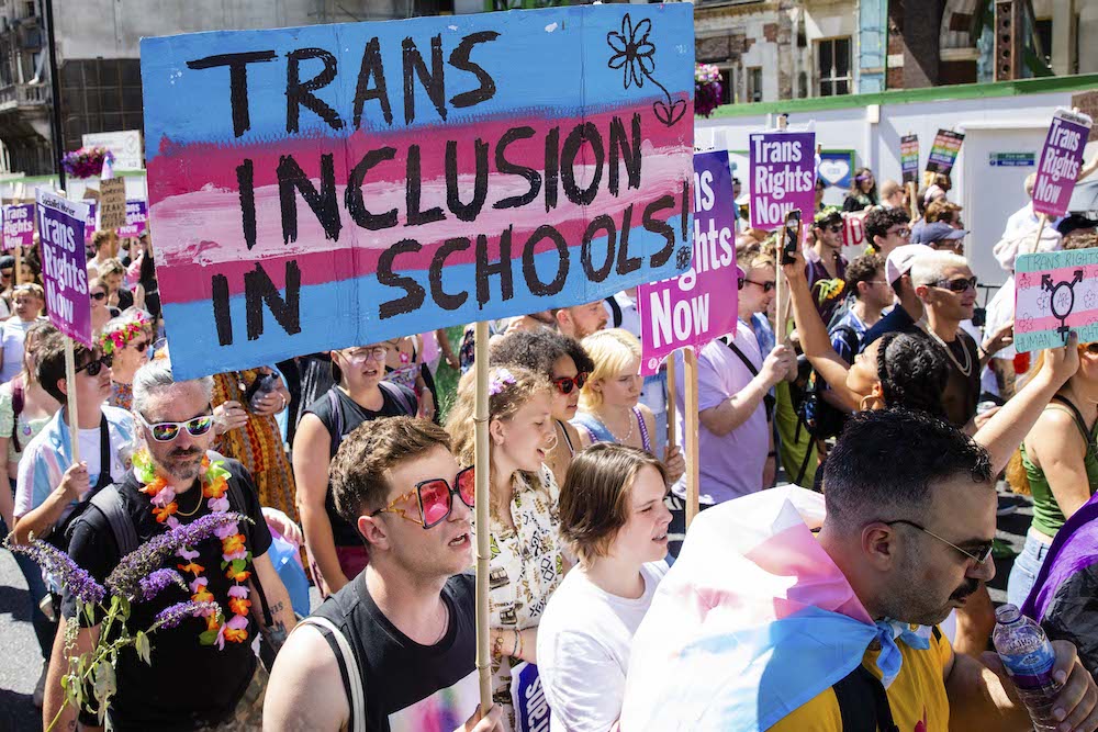 A protesters London Trans+ Pride holds a sign reading: "Trans inclusion in schools"