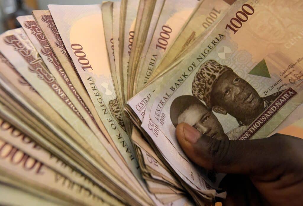 A man holds a wad of naira in his hand