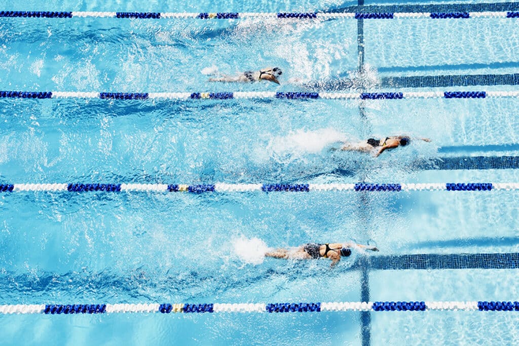 Young competitive swimmers racing in outdoor pool overhead view.