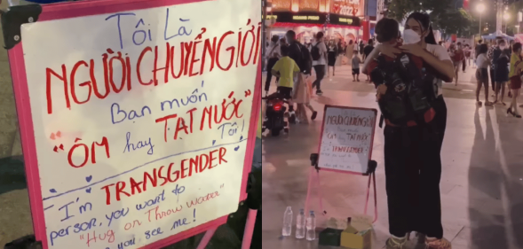 Trans woman stands in street with 'hug me or throw water on me' sign