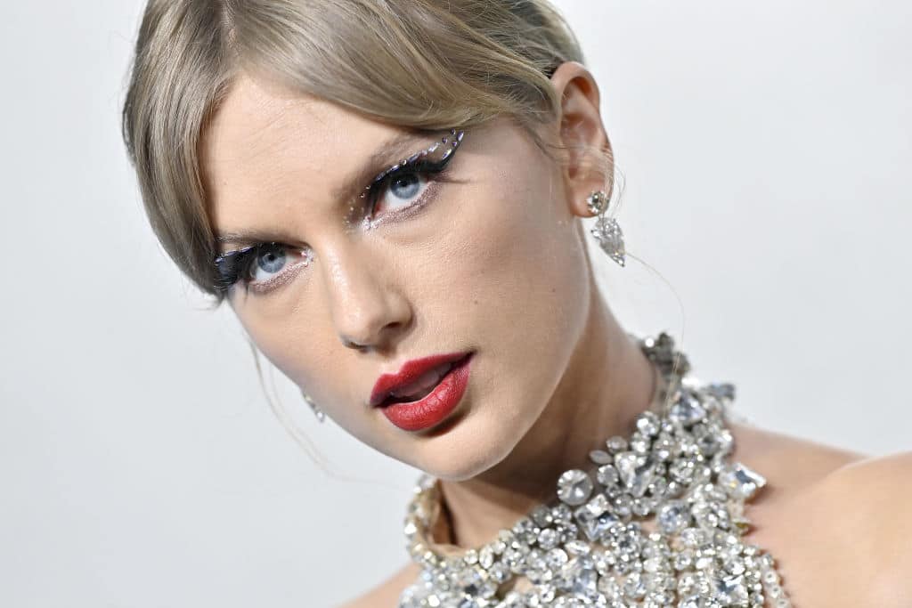 Close-up photo of Taylor Swift with her hair pulled back, red lipstick and a dress made out of strings of diamonds
