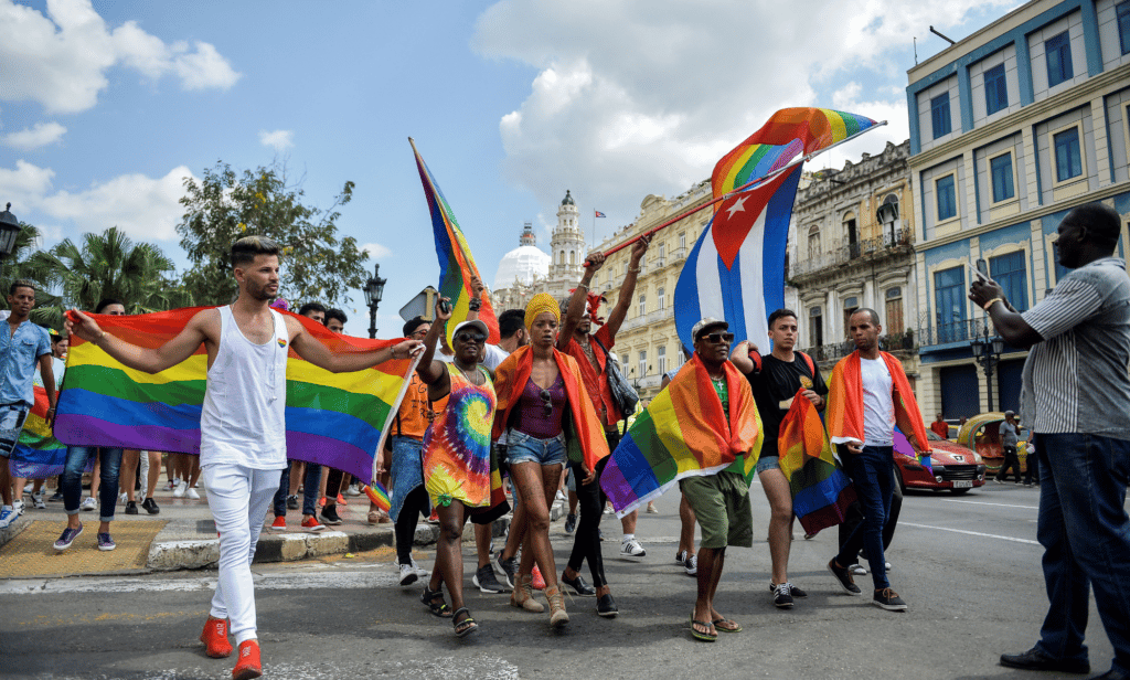 LGBTQ+ campaigners hold up rainbow Pride flags and Cuban flags as they march together