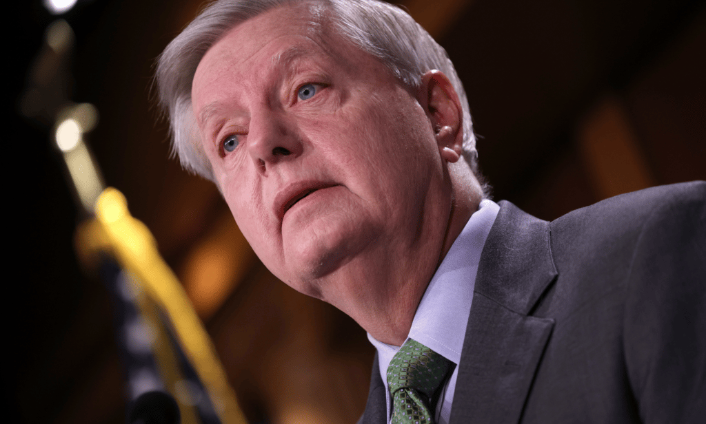 Lindsey Graham wears a suit and tie as he speaks to someone off camera