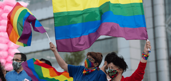 A crowd of people in Chile wave LGBTQ+ Pride flags