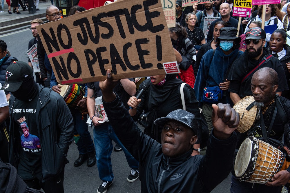 Protesters hold a sign that reads "no justice, no peace" during a march in London