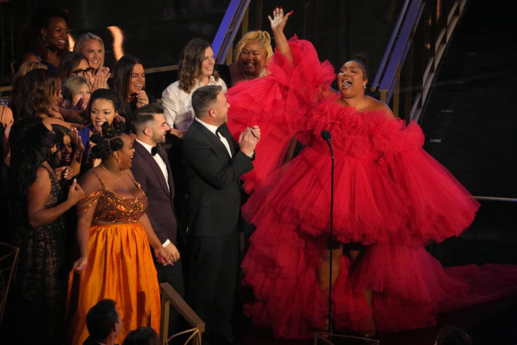 Lizzo in a large, tulle red dress, hand raised in the air
