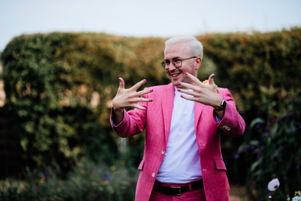 A photo of Tom Pashby, wearing a pink suit over a white shirt