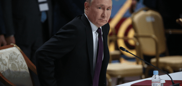 Vladimir Putin taking a seat during a political address