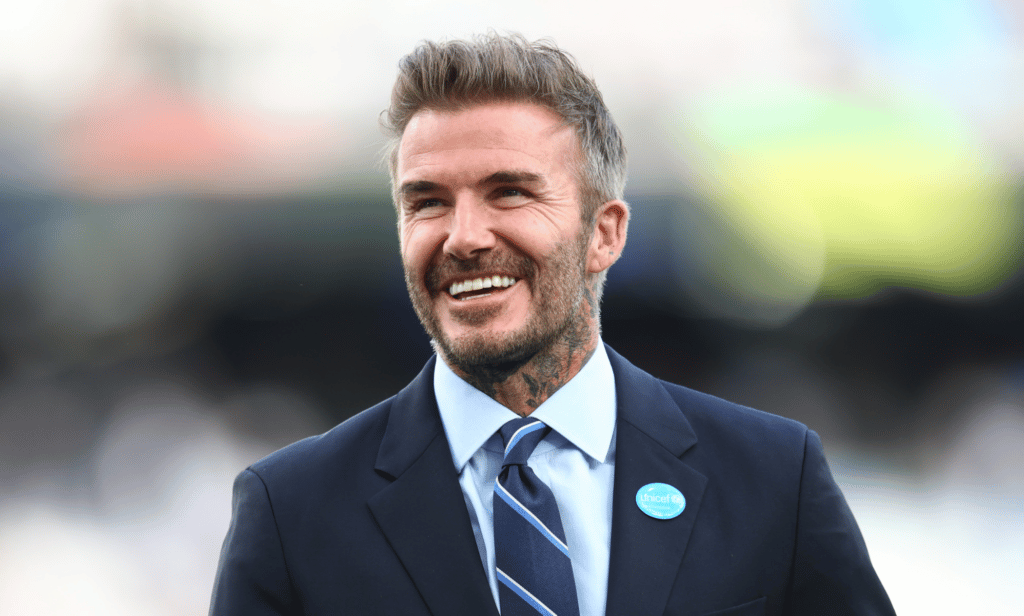 David Beckham smiles as he wears a suit and tie