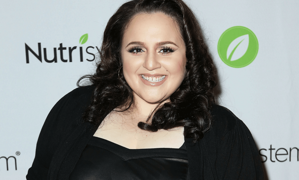 Nikki Blonsky smiles at the camera while wearing a black outfit