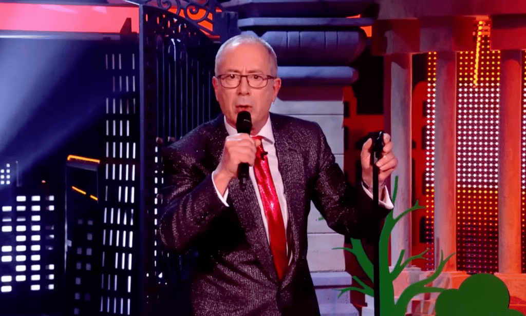 Ben Elton speaks into the microphone during the opening monologue to Channel 4's Friday Night Live special