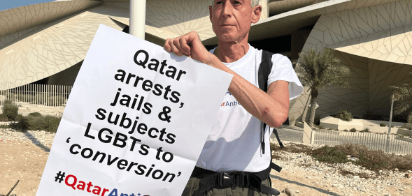 Peter Tatchell holds up a sign protesting against Qatar's anti-LGBTQ+ regime