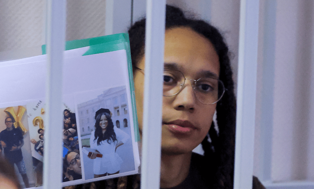 Brittney Griner holds photos inside a defendants' cage before a Russian court hearing