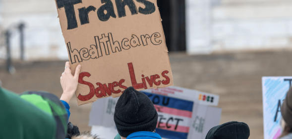 A person holds up a sign reading 'trans healthcare saves lives'