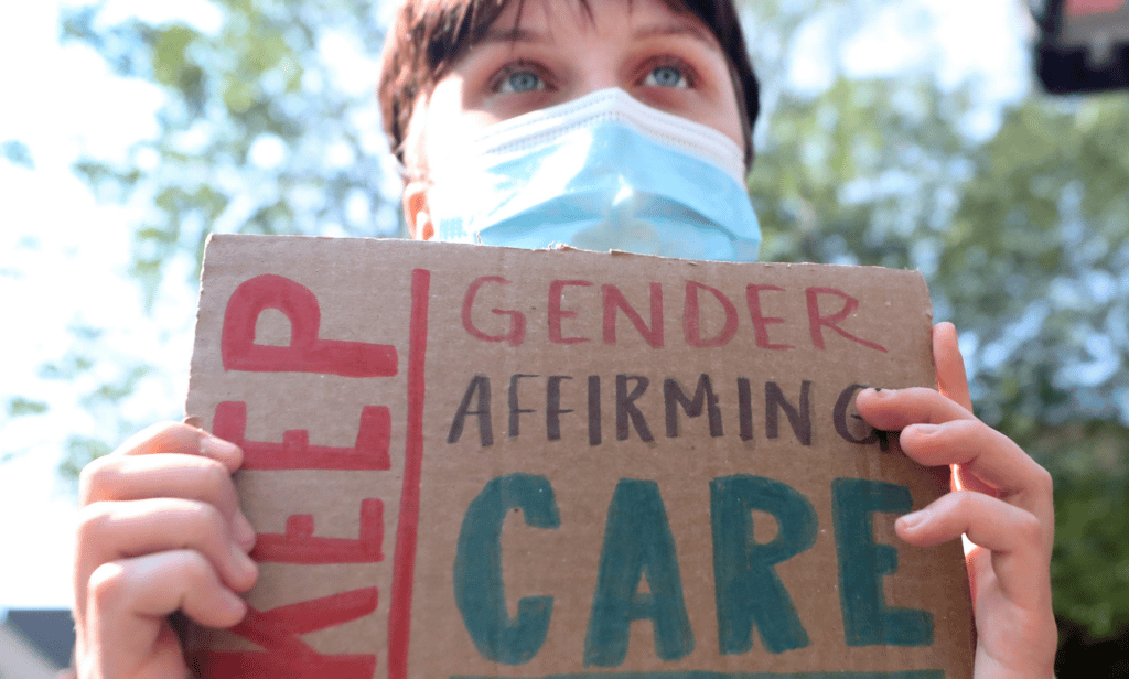 A person holds up a sign reading 'Keep gender-affirming care' during a demonstration in support of healthcare for trans youth