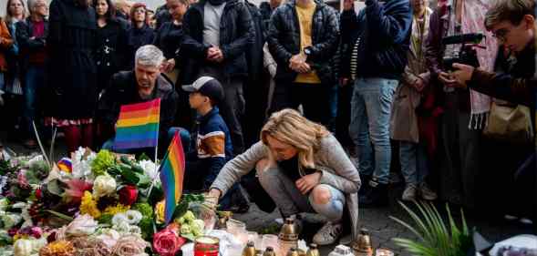 People attend the vigil in Slovakia, placing Pride flags and candles, following the shooting where two men were killed