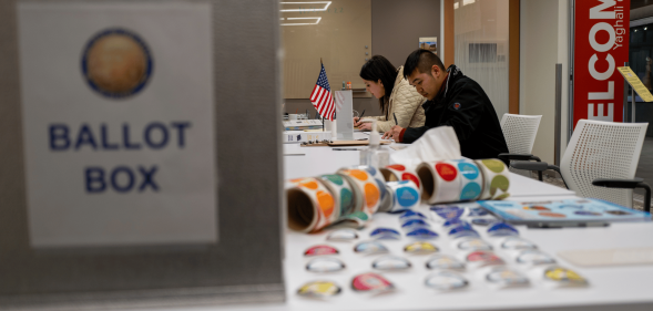 People sit at a table while others come in to vote during the US midterm elections