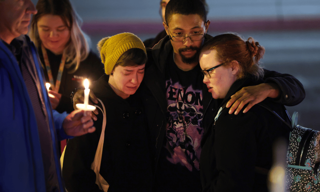 People hold a vigil at a makeshift memorial near the Colorado Springs nightclub, Club Q, which was the scene of a mass shooting