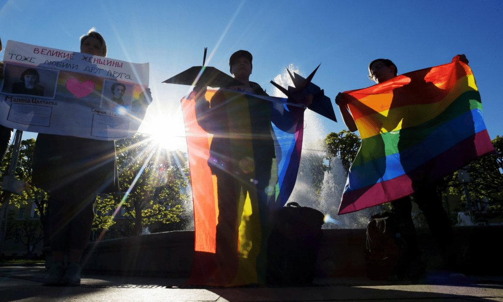Activists hold up the rainbow LGBTQ+ Pride flag during a protest in Russia