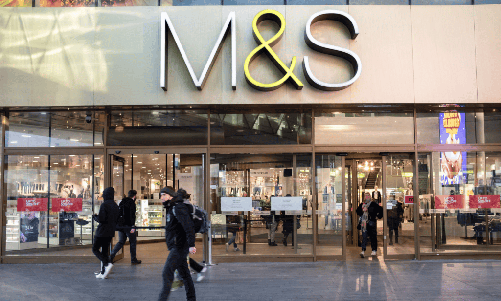 A picture of a Marks & Spencer storefront with the letters 'M&S' displayed on the building as people walk by the store