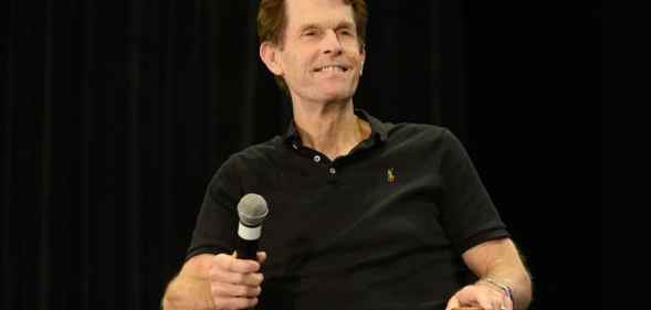 Kevin Conroy holds a microphone on stage