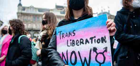 A trans protester holds a placard saying trans liberation now during a demonstration