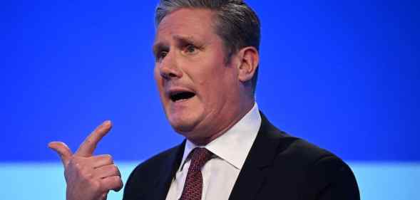 A screenshot of Labour leader Keir Starmer standing in front of a blue background and talking at a political conference