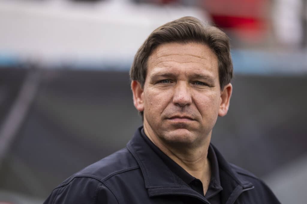 Florida Governor Ron DeSantis wearing a black shirt and jacket looks on before the start of a game between the Georgia Bulldogs and the Florida Gators