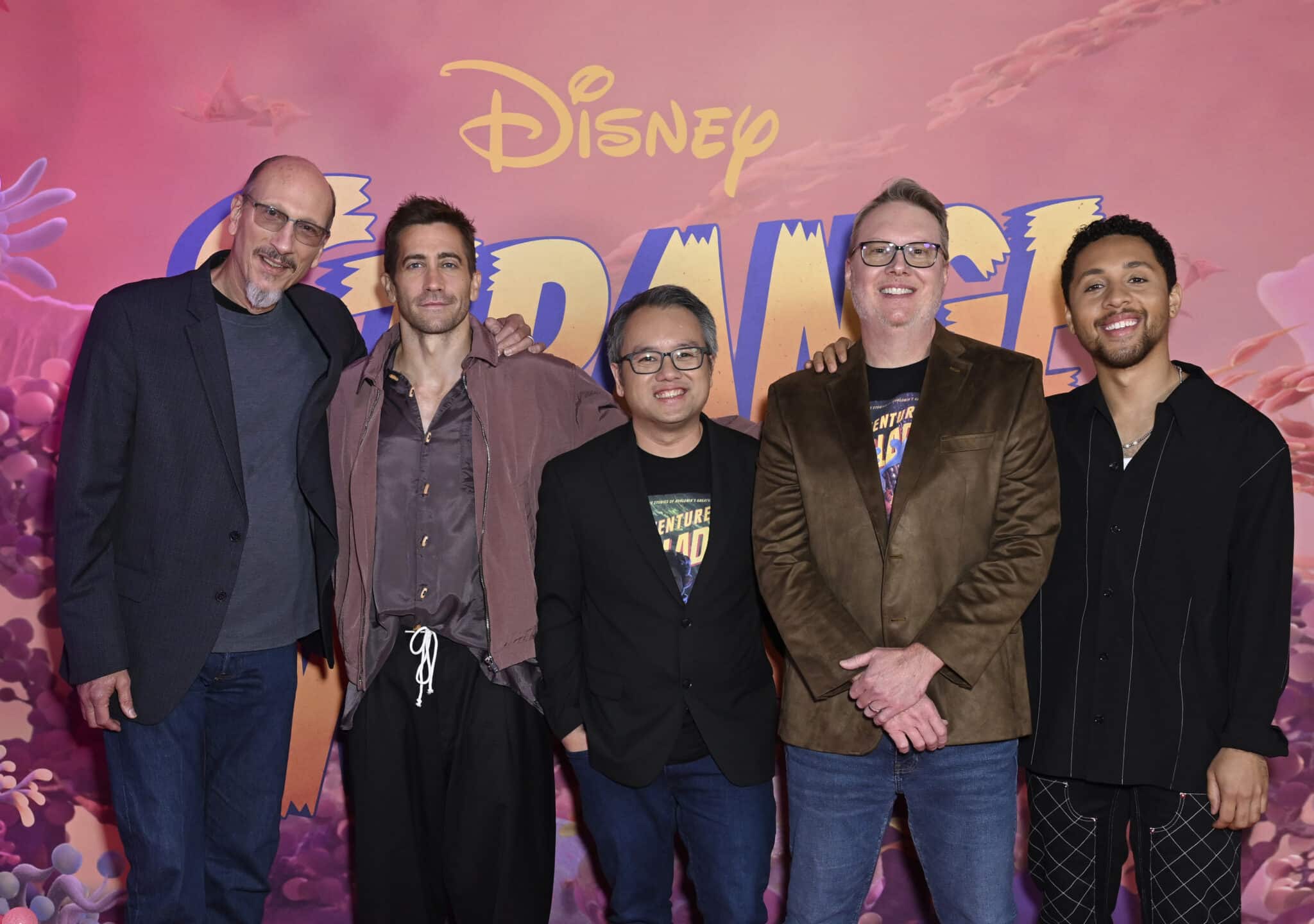 Roy Conli, Jake Gyllenhaal, Qui Nguyen, Don Hall and Jaboukie Young-White standing infront of a pink Strange World backdrop.