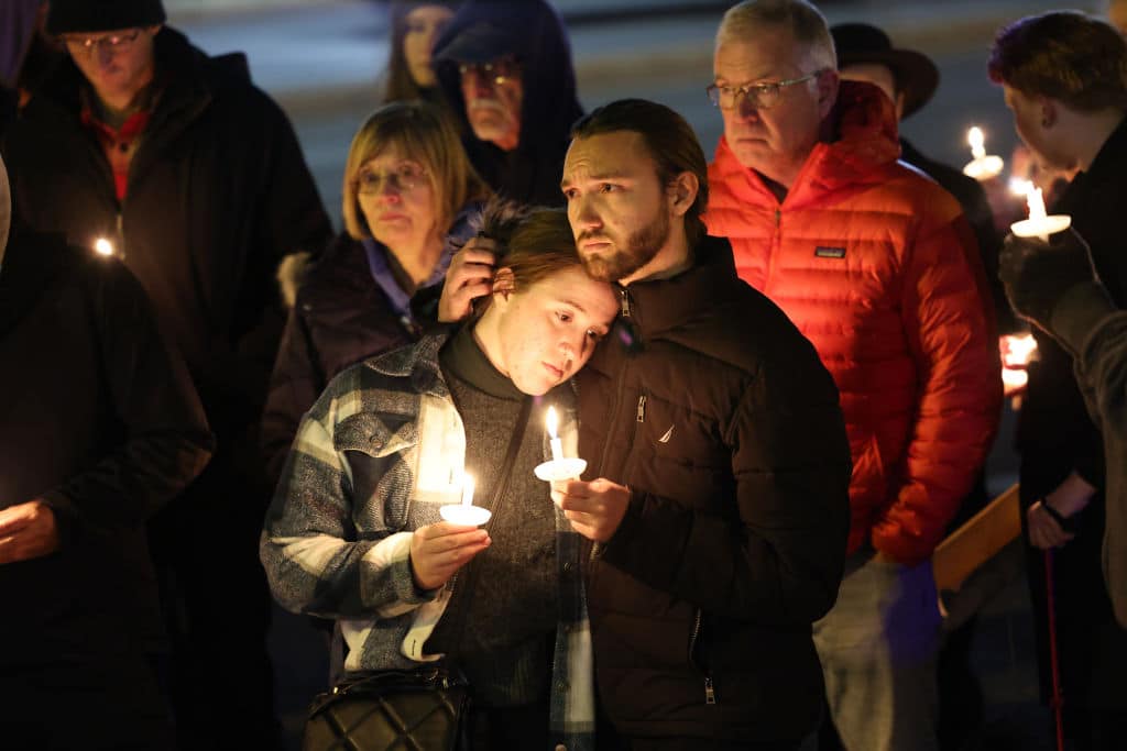 People hold a vigil at a makeshift memorial near the Club Q nightclub on November 20, 2022.
