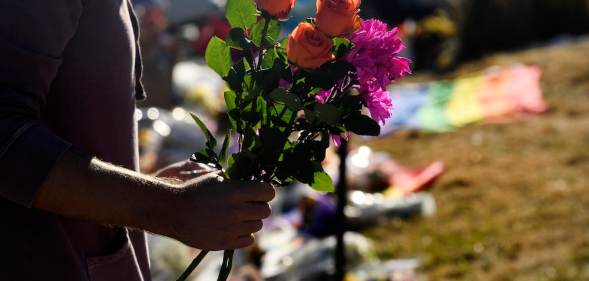 A closeup of a mourner's arm holding flowers to leave at the memorial for the victims of the Club Q shooting in Colorado Springs