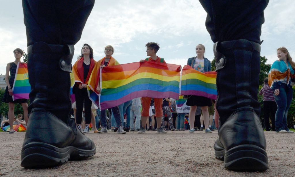 Activists stand side-by-side during a protest holding up rainbow LGBTQ+ flags in Russia