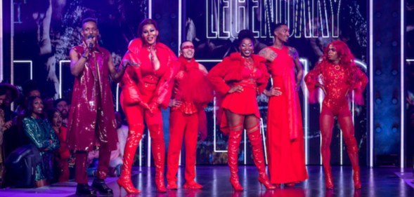 A screengrab from HBO's Legendary showing its contestants dressed in their red outfits on stage and also standing to the side dressed in his purple outfit is actor and dancer Dashaun Wesley who is the MC in the show.(HBO Max)