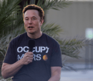 Elon Musk stands with a microphone, wearing an "occupy Mars" T-shirt